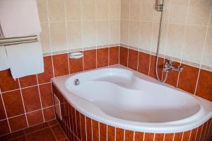 デブレツェンにあるArany Patkó Panzióのタイル張りの客室で、バスルーム(大型バスタブ付)が備わります。