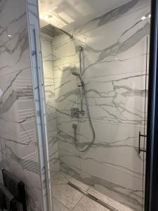 y baño con ducha y paredes de mármol blanco. en Innsbruck home, en Innsbruck