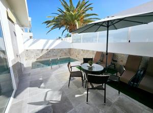 a patio with a table and chairs and an umbrella at Villa Blue Moon in Tías