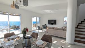 ein Wohnzimmer mit einer Couch und einem Tisch mit Stühlen in der Unterkunft Villa Galatea Stunning First Line Beachfront in Klorakas