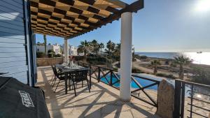 eine Terrasse mit Tisch und Stühlen sowie Strand in der Unterkunft Villa Galatea Stunning First Line Beachfront in Klorakas