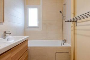 a bathroom with a tub and a sink and a window at petit cocon in Créteil +17 photos