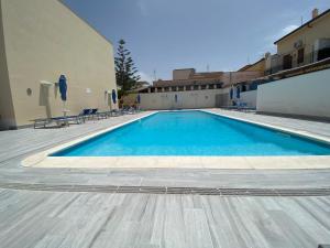 a swimming pool with chairs and a building at Residence Le Perle Beach in San Vito lo Capo
