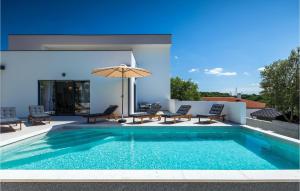 a swimming pool with chairs and an umbrella next to a house at Villa My Hana in Pula