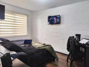 a bedroom with a laptop on a bed with a tv on the wall at Hotel Bellavista Quito in Quito