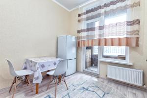 eine Küche mit Tisch und Stühlen und einem Kühlschrank in der Unterkunft Уютная квартира на левом берегу in Astana + 10 Fotos