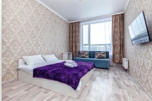 ein Schlafzimmer mit einem lila Bett und einem blauen Sofa in der Unterkunft Уютная квартира на левом берегу in Astana