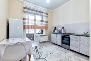 eine Küche mit weißen Geräten sowie einem Tisch und Stühlen in der Unterkunft Уютная квартира на левом берегу in Astana