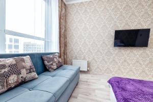 ein Wohnzimmer mit einem blauen Sofa und einem Fernseher in der Unterkunft Уютная квартира на левом берегу in Astana