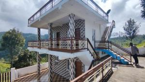 a man standing on the side of a building with a balcony at Sandy 4 Bhk Homestay - Only Adults Allowed in Ooty