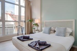 Un dormitorio con una gran cama blanca con toallas. en Apartamentos Uncibay Premium, en Málaga