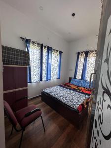 a bedroom with a bed and a chair and windows at Sandy 4 Bhk Homestay - Only Adults Allowed in Ooty