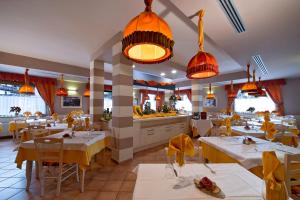 ein Restaurant mit weißen Tischen, Stühlen und Lampen in der Unterkunft GH Hotel Piaz in Pozza di Fassa