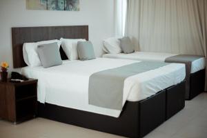 two beds in a hotel room with white sheets at Hotel Safira Brasília l SLEEP HOTÉIS in Taguatinga +10 photos