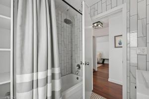 a bathroom with a tub and a shower curtain at 4 Bedroom Luxury House, Free Parking, Next to LRT, Kitchener Downtown, near Chicopee Ski Club in Kitchener +18 photos