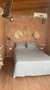 un lit dans une chambre avec un mur de briques dans l'établissement Chacrinha pousada e restaurante Chalé Seriema, à Caldas Novas