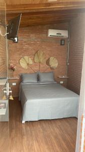 une chambre avec un lit et un mur de briques dans l'établissement Chacrinha pousada e restaurante Chalé Seriema, à Caldas Novas