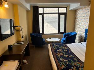 a hotel room with a bed and chairs and a window at Book inn apartment in Srinagar