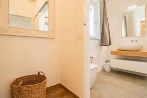 een badkamer met een wastafel, een toilet en een spiegel bij Apartment Mare di Spartaia in Procchio