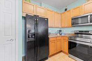 a black refrigerator in a kitchen with wooden cabinets at 5 Star Resort 11th Fl Stunning Sunrise 2BR 2BA King Suite,Pools ,Shuttle or Walk to Beach in Destin