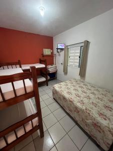 a bedroom with two bunk beds and a television at Pousada Iguape Apartamentos - Ilha Comprida in Ilha Comprida