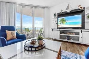 sala de estar con TV y silla azul en Sunrise Surprise 9th floor 2BR 2 BA King Suite Beach shuttle, heated pool!, en Destin