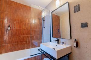 a bathroom with a sink and a mirror and a tub at Grand Hôtel De La Seine in Rouen