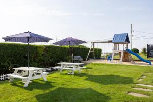 two picnic tables with umbrellas and a playground at Beachside Village Resort in Falmouth