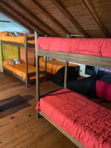 Habitación con 3 literas y un cojín rojo. en HOSTEL CASA C Alojamiento, Coworking y Centro Cultural, en Villa General Belgrano 22 fotos más
