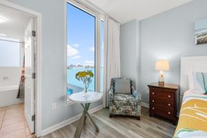 Un dormitorio con una cama y una silla y una ventana. en Palms Resort 2 BR King Suite Poolside Shuttle, en Destin