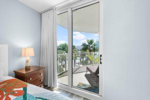 Un dormitorio con un gran ventanal con vista a un balcón. en Palms Resort 2 BR King Suite Poolside Shuttle, en Destin