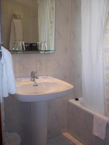 ein Badezimmer mit einem Waschbecken, einem Spiegel und einer Badewanne in der Unterkunft Hotel Suiza in Arzúa