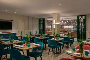 a restaurant with wooden tables and blue chairs at Sonesta Miami Airport in Miami +43 photos