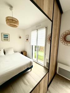 a bedroom with a bed and a large window at Maison à 100m de la mer in Hermanville-sur-Mer