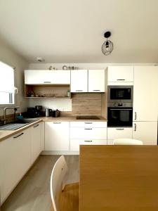 a white kitchen with white cabinets and a table at Maison à 100m de la mer in Hermanville-sur-Mer
