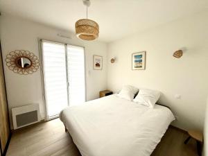 a bedroom with a white bed and a large window at Maison à 100m de la mer in Hermanville-sur-Mer