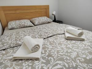 a bed with two pillows and towels on it at Apartman Panorama in Tomislavgrad
