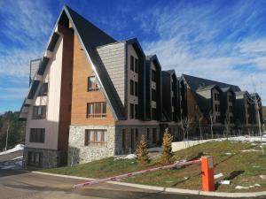 a building with a black roof on a street at DivčiNova apartman Gnezdo in Divčibare +14 photos