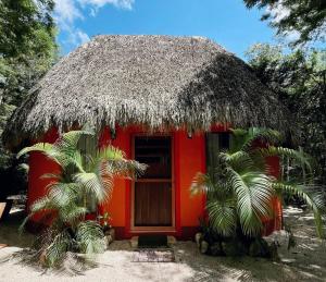 a small red house with a thatched roof at Hotel Boutique Cenote Secreto Maya in Valladolid
