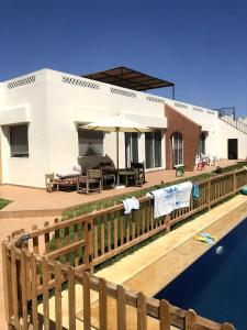 a house with a wooden fence next to a body of water at premium farmhouse with pool Rabat in Rabat