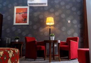 a waiting room with red chairs and a lamp at Grand Casamora Hotel in East Legon