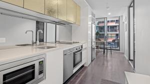 una cucina bianca con lavello e fornello di The Downtown Nest a Melbourne