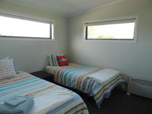 two beds in a small room with two windows at Essene Country Lodge in Cambridge