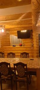 Un comedor con mesa y sillas y un televisor. en Cabana Deluț, en Borşa