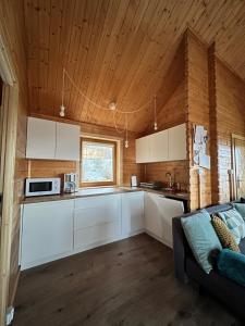 una cocina con armarios blancos y un sofá en una habitación en Domki Habzówka, en Ostre