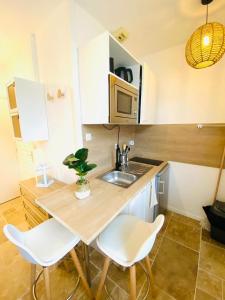 a kitchen with a sink and a table with two chairs at Bienvenue à Santorin - Caen centre in Caen
