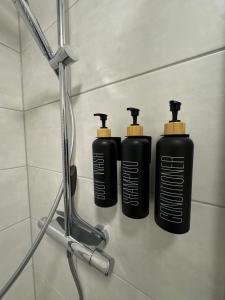 three black shampoo bottles on a shelf in a bathroom at Modernes Serviced Apartment - FeWo Morgenglanz in Berchtesgaden +16 photos