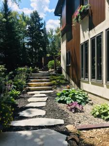 a garden with rocks and flowers next to a building at PETIT COIN DE PARADIS in Sainte Anne des Lacs