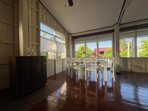 a room with a table and chairs and windows at Once in Lampang Guesthouse in Lampang