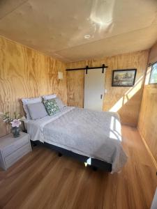 ein Schlafzimmer mit einem Bett in einem Zimmer mit Holzwänden in der Unterkunft Mangawhai studio in Mangawhai